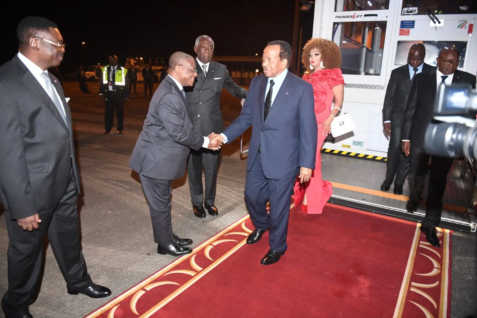 Troisième Image de Politique. Après leur participation au sommet Russie-Afrique, le président camerounais Paul Biya et son épouse Chantal sont rentrés à Yaoundé. L'accueil chaleureux du Premier ministre et du ministre secrétaire général de la présidence marque leur retour dans la capitale politique. Quels bénéfices ou défis le Cameroun pourrait-il rencontrer suite à sa participation à ce sommet ?