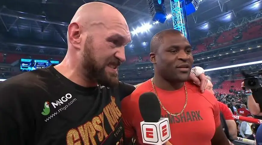 Image de Célébrités. Tyson Fury rend hommage à son futur adversaire, Francis Ngannou, avant leur combat à Riyad, en Arabie Saoudite, le 28 octobre. À travers une vidéo touchante publiée sur la page "Arena MMA", Fury a loué le parcours extraordinaire de Ngannou, en soulignant sa détermination à atteindre le sommet de la boxe mondiale malgré les obstacles. Francis Ngannou, parti de l'Afrique avec un grand rêve, est devenu une star mondiale grâce à son engagement, son évolution et sa persévérance. Fury a témoigné de sa propre admiration pour Ngannou, rappelant que lorsqu'il disait qu'il combattrait contre lui, il ne se moquait pas. Certes, le combat n'a pas de titre en jeu et peut comporter plus de 8 rounds, mais il est indéniable qu'il attire l'attention et les affaires. Qui sera le vainqueur d'après vous ?